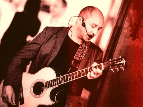 eine Person mit einem Mikrofon, die eine Gitarre spielt